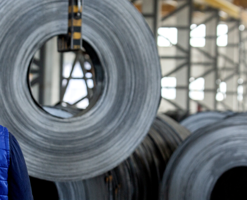 Trabajador en fábrica de acero observando rollos metálicos — propuesta de la Comisión Europea para proteger el mercado siderúrgico.